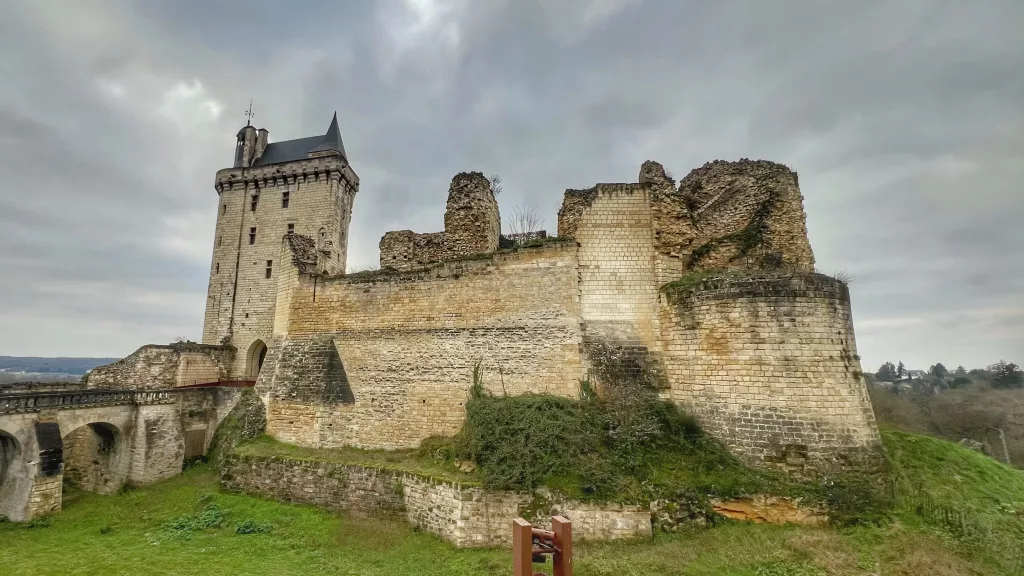 Vista de la Fortaleza de Chinon, un castillo medieval en ruinas con una torre imponente y muros de piedra en el Valle del Loira, Francia.