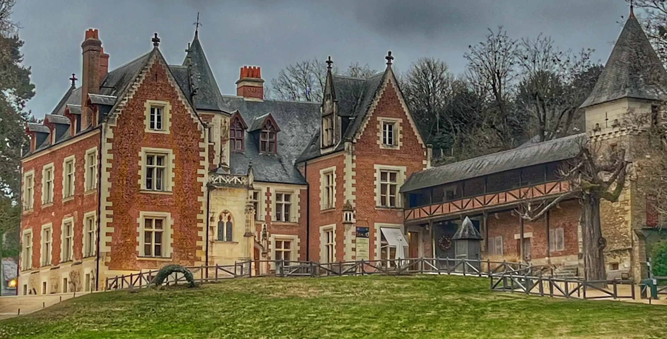 Vista frontal del Château du Clos Lucé en Amboise, Francia, con su característica fachada de ladrillo rojo y techo gris.