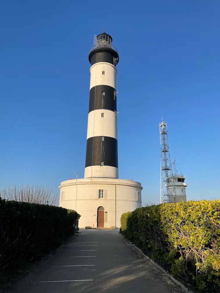 Faro de Chassiron en la isla de Oléron, Francia, con su característica estructura en blanco y negro bajo un cielo despejado.