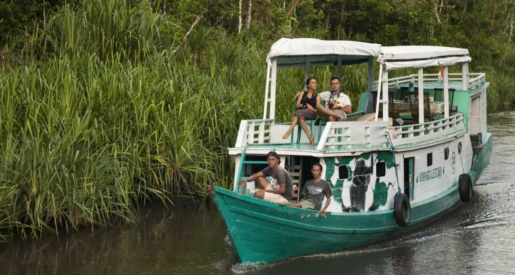 Klotok navegando por el río en Borneo, rodeado de vegetación