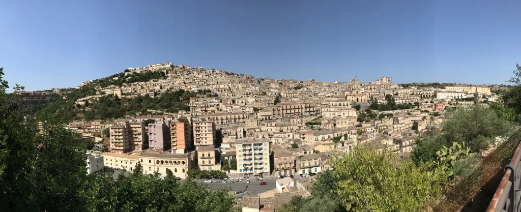Vista panorámica de Modica en Sicilia con sus edificios históricos y colinas verdes.