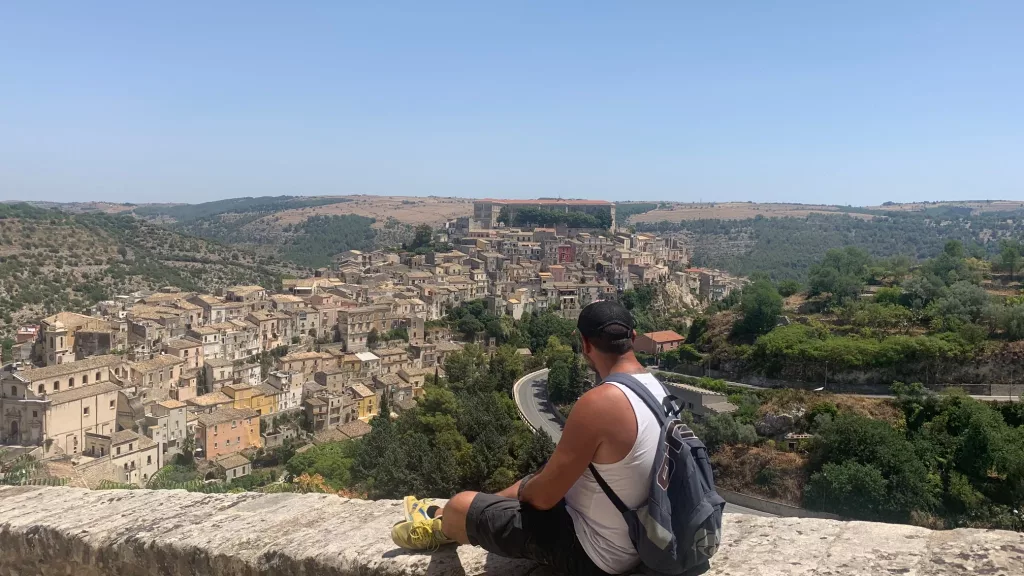 Vista panorámica de Ragusa en Sicilia con un viajero contemplando el paisaje.