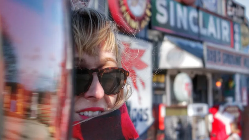 Ana sonriente con gafas de sol y fondo de carteles vintage en la Ruta 66