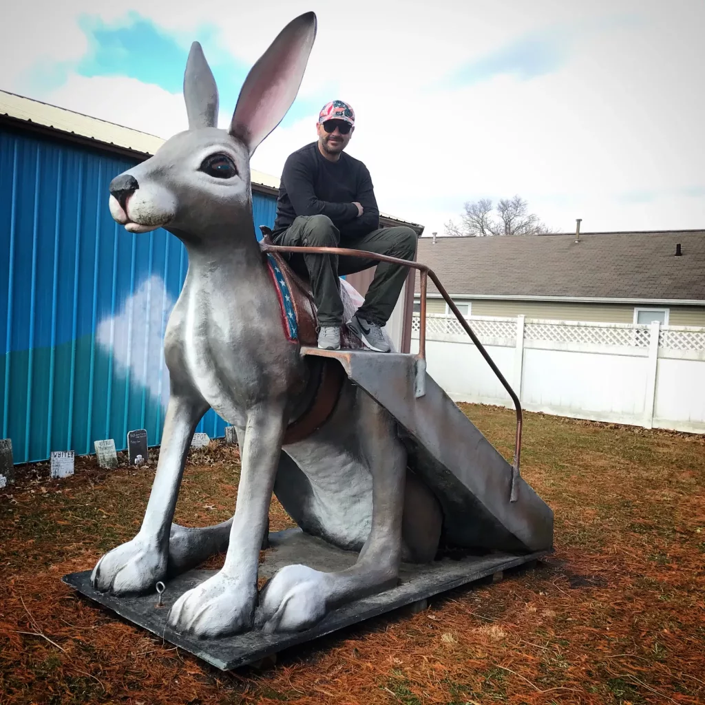 Miguelito sentado sobre una enorme estatua de jackalope en la Ruta 66