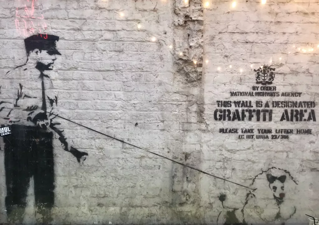 Graffiti icónico en Londres atribuido a Banksy con un policía paseando a un perro
