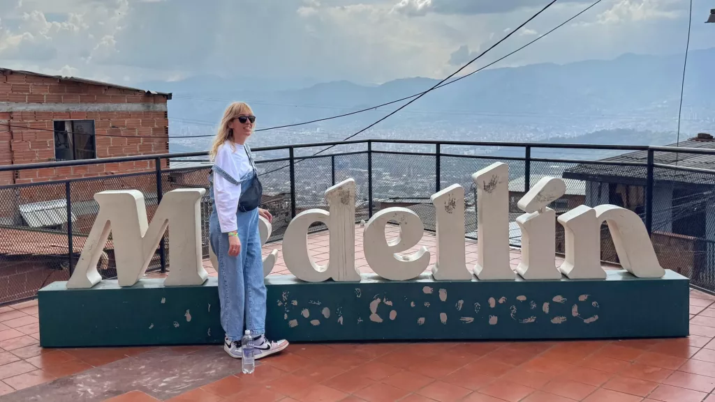Ana junto al icónico cartel de Medellín con vistas panorámicas