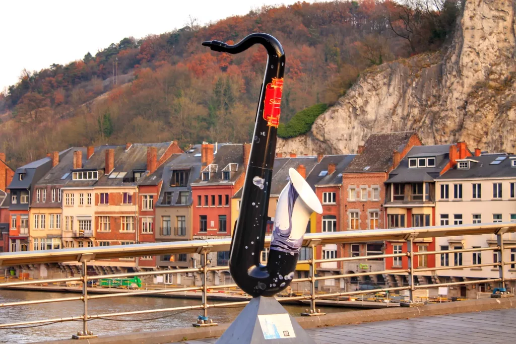 Escultura de un saxofón en Dinant, Bélgica, junto al río Mosa y las casas coloridas.