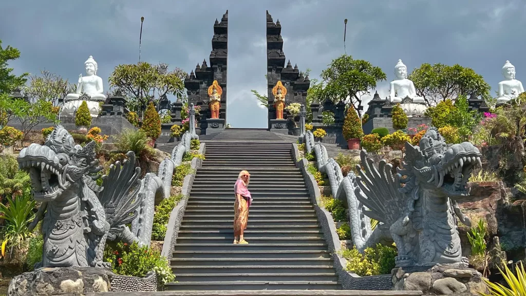 Ana en las escaleras del templo Brahmavihara-Arama en Bali, rodeada de estatuas y una arquitectura impresionante